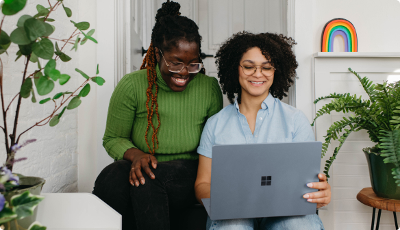 Couple of friends smiling looking at their laptop